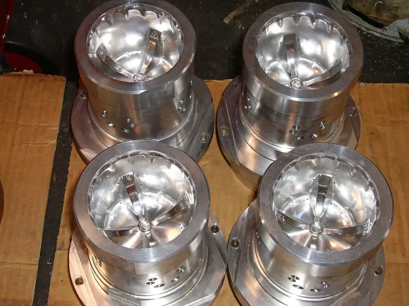 Four identical precision machined cylindrical components on cardboard